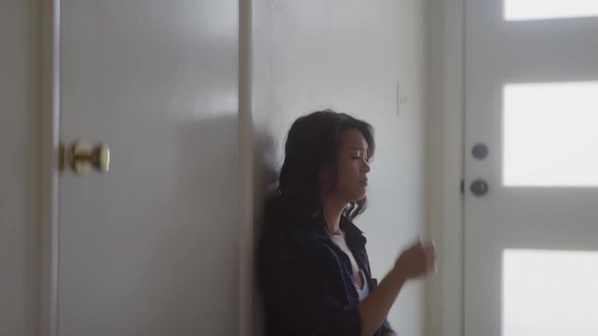 Sad woman leaning against the wall and sitting on the floor putting her hand on her face
