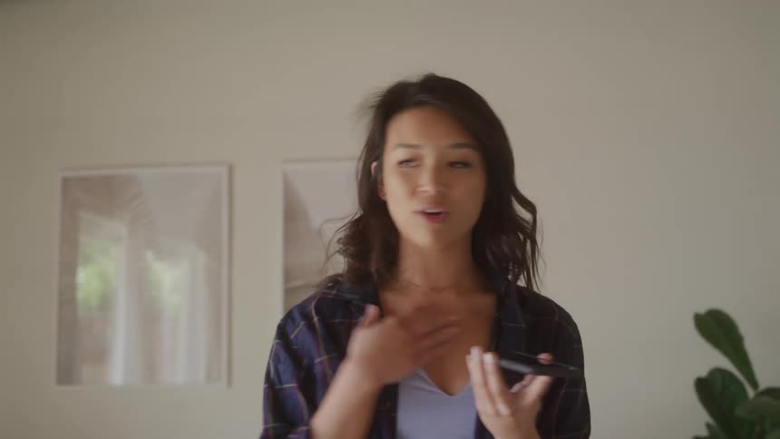A young woman speaks on speakerphone gesturing anxiously while explaining something