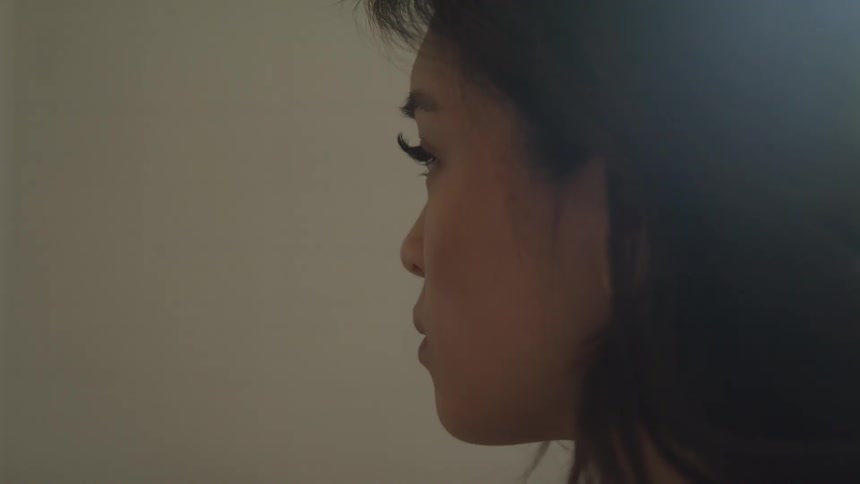 A woman in side profile against a plain background looking calm and thoughtful