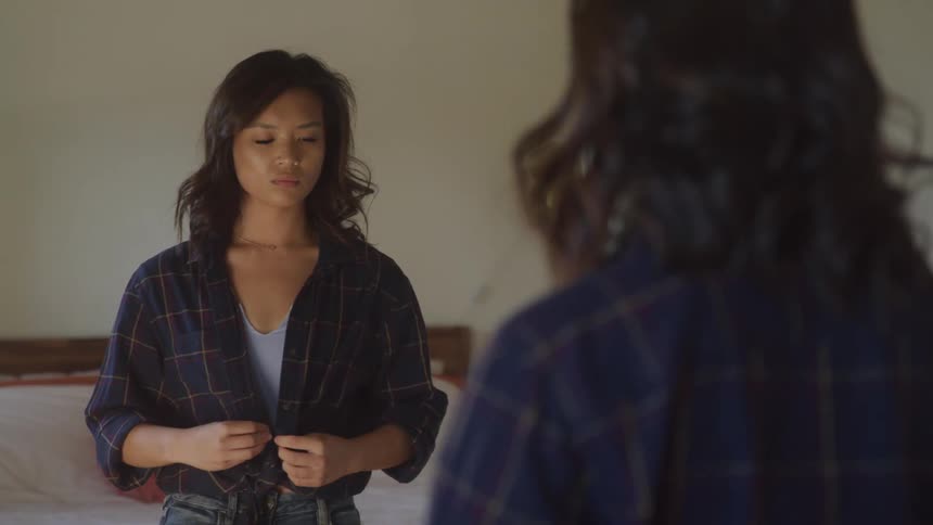 Woman in front of the mirror fixing her hair and looking at her clothes