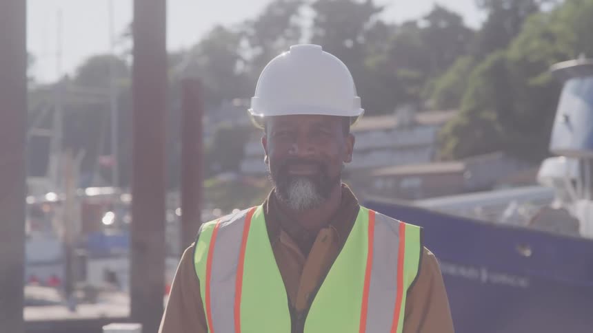 Man in helmet and vest stands in a port