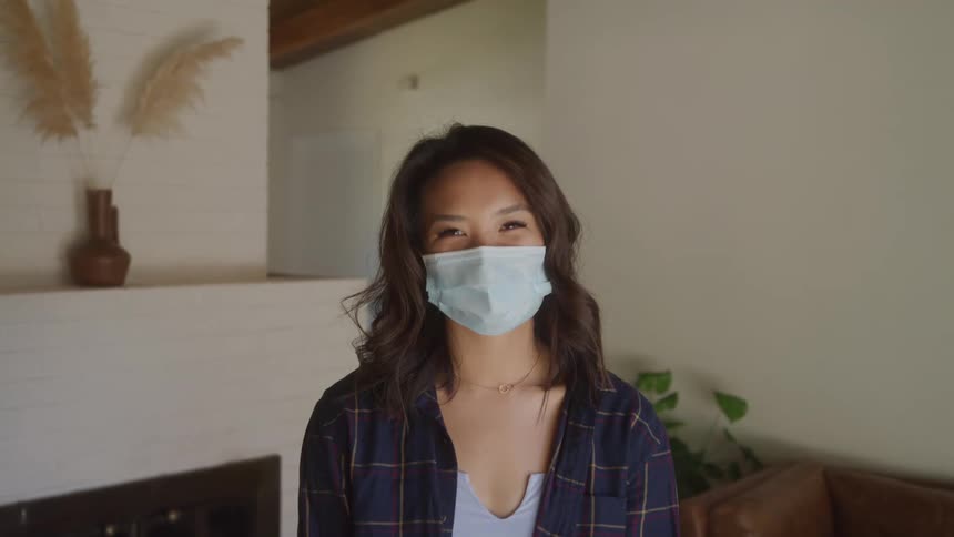A woman in a living room wearing a mask but looking happy