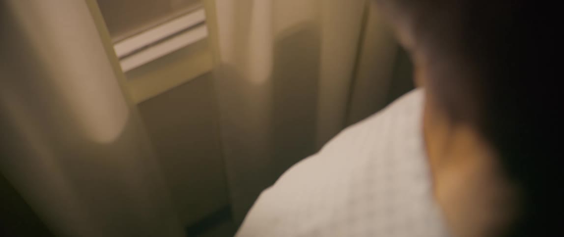 A man clenches his hands by the window