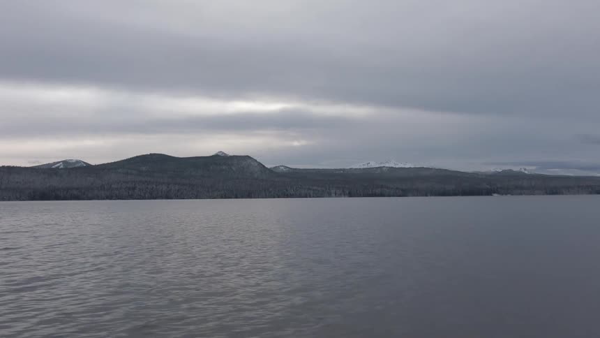 A large lake under a cloudy sky with mountains in the background