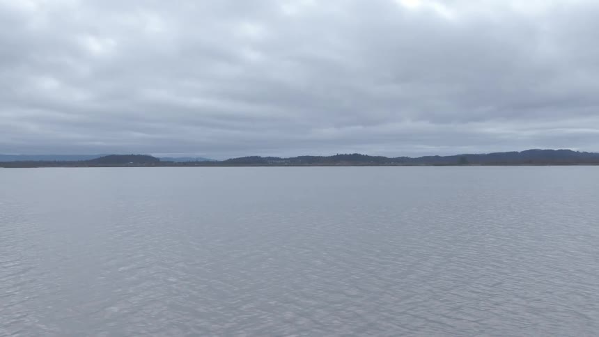 A large lake with mountains in the background and a cloudy sky