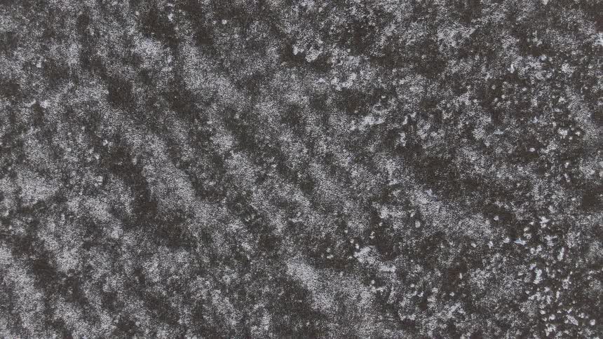 Closeup of a textured surface with a granular frostlike pattern on a dark background