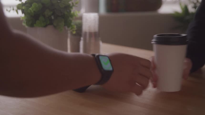 Customer purchasing coffee from his smartwatch on a payment processor at a coffee shop