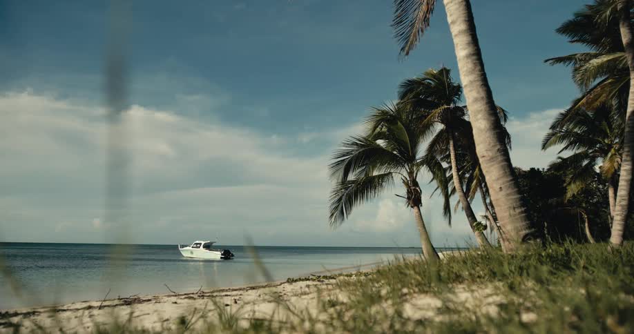 A small boat sits in the water just off the coast of a beach