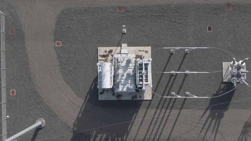 An aerial view of an industrial electrical substation showing transformers and power lines