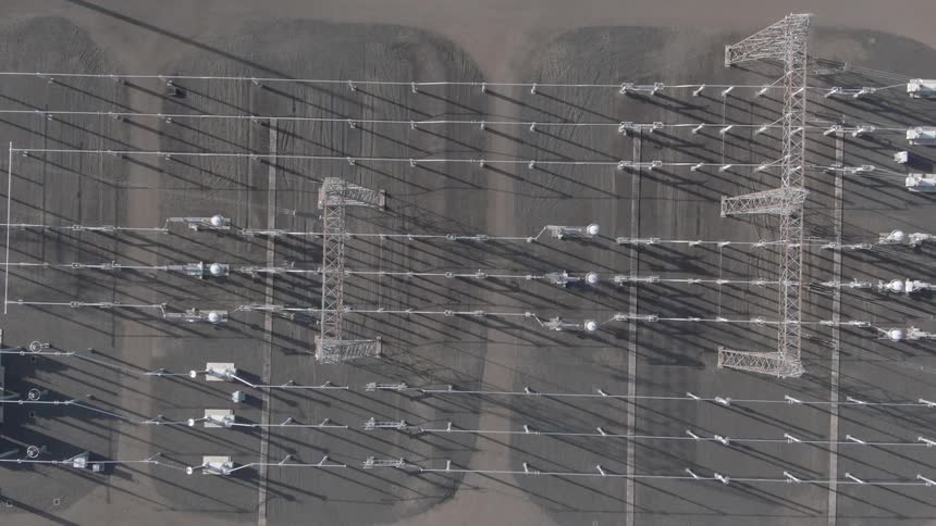 Topdown aerial view of an electrical substation with towers transformers and power lines casting shadows