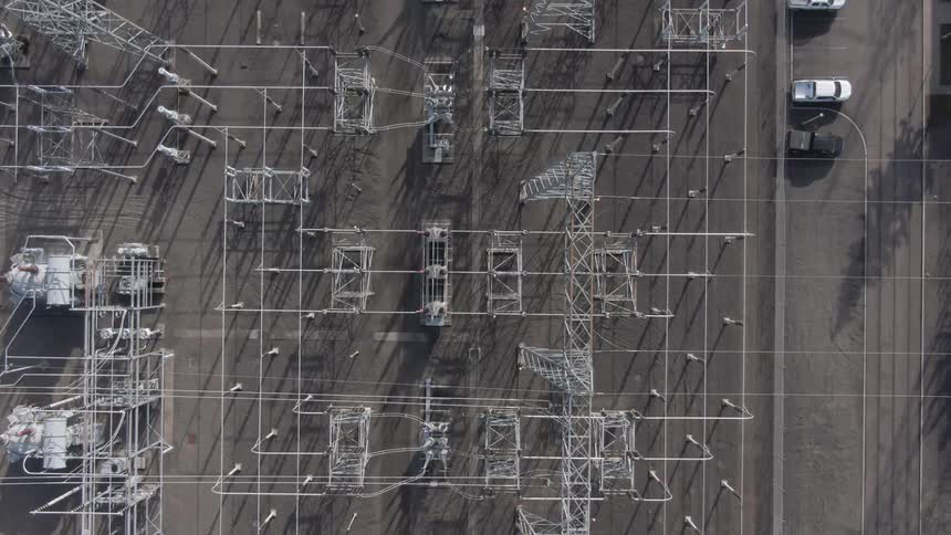 Aerial view of an industrial substation with metal structures and parked cars