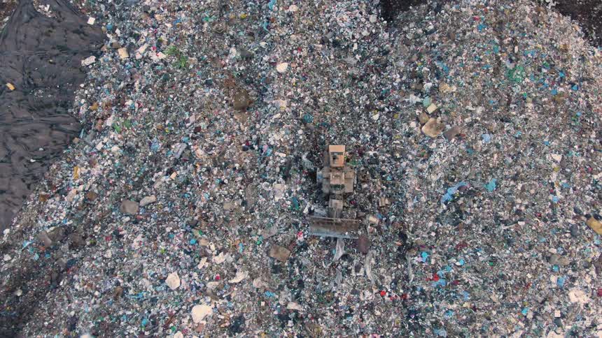 The bulldozer drives in the landfill