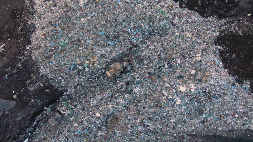 Birds eye view of bulldozers plowing through a landfill