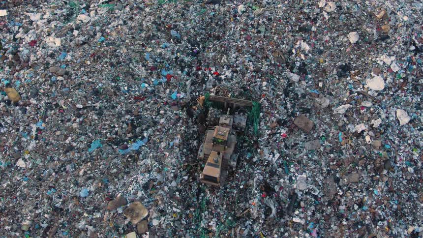 A tractor pushes garbage out of the way to make a path