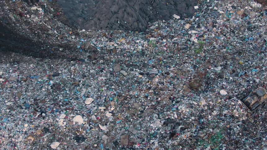 Aerial view of a tractor cleaning a huge openair landfill