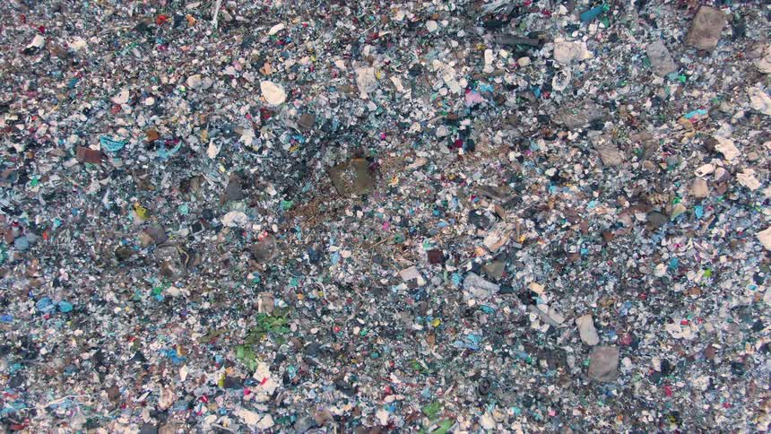 Aerial view of a large area covered in multicolored garbage showing severe pollution