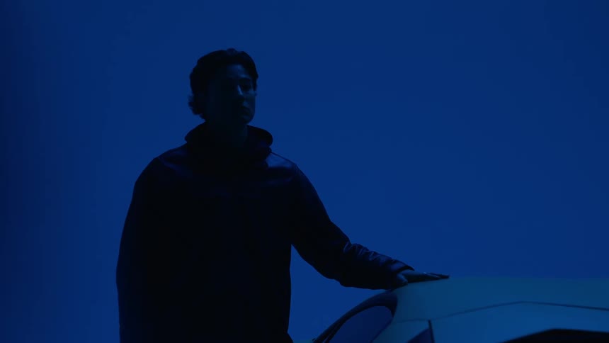 Silhouette of a man in a studio with his hand resting on a vehicle
