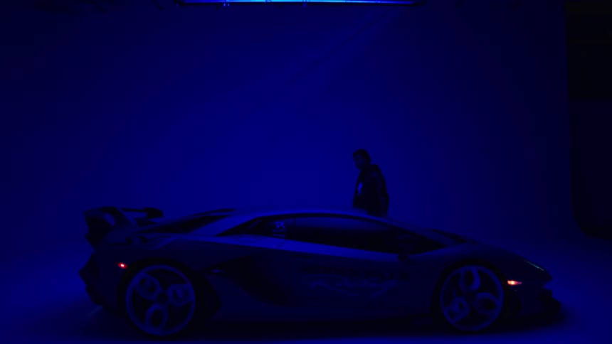 A man walks over to the sports car in the showroom