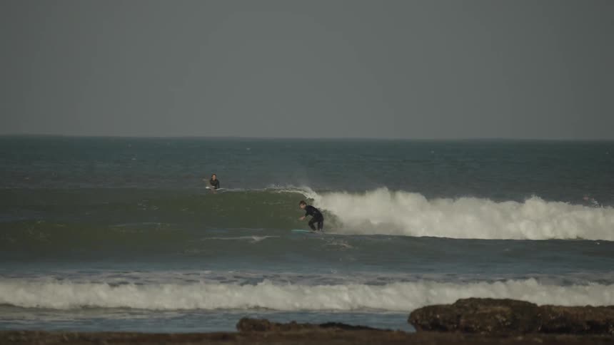 A group of people are surfing ocean waves on a cloudy day