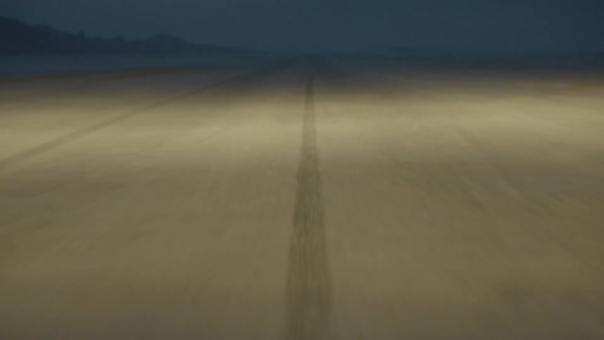 A road is being traveled down at high speed at night