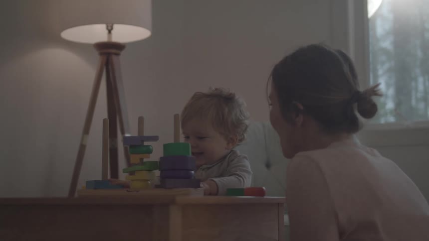 Mother watching her baby daughter playing with toys