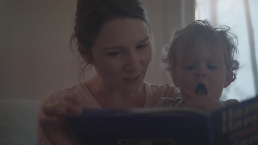 Mother reading a book with her baby on her lap