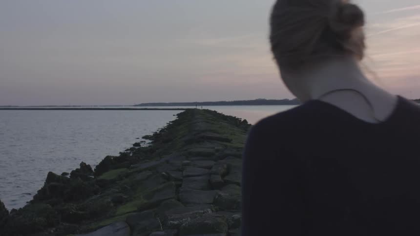 Woman walking on rocks in the middle of the sea