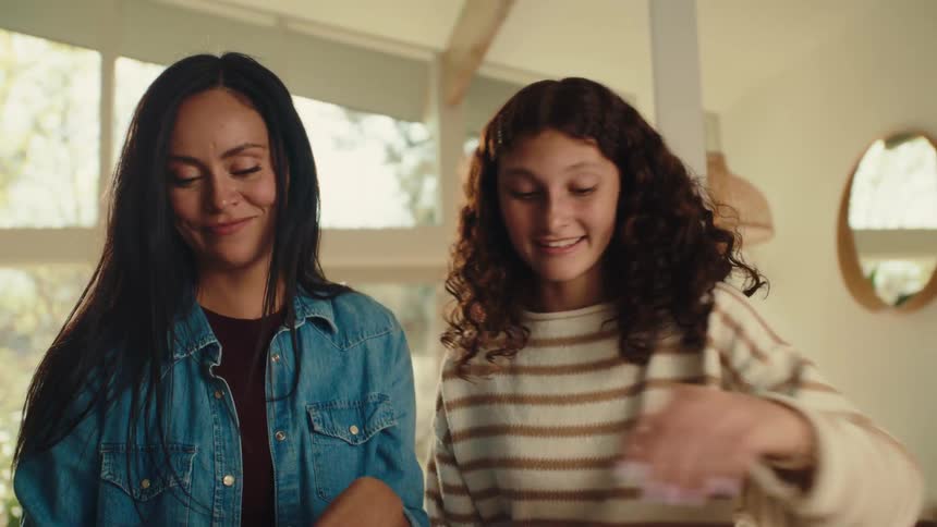 A mother and daughter are using a cookie cutter to make cookies