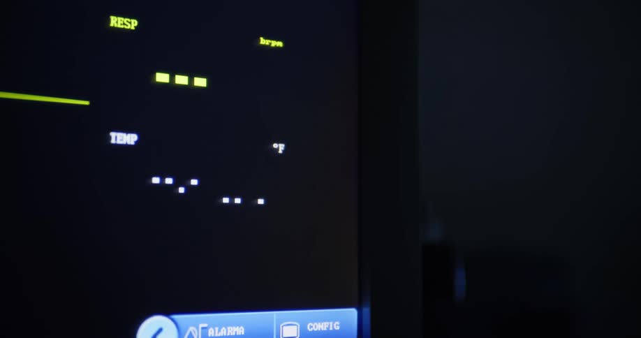 Closeup of a medical monitor showing a high temperature in a dark hospital room