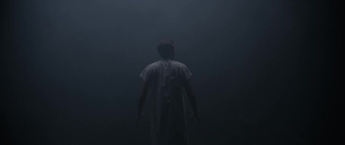 A man walks in the dark room full of fog