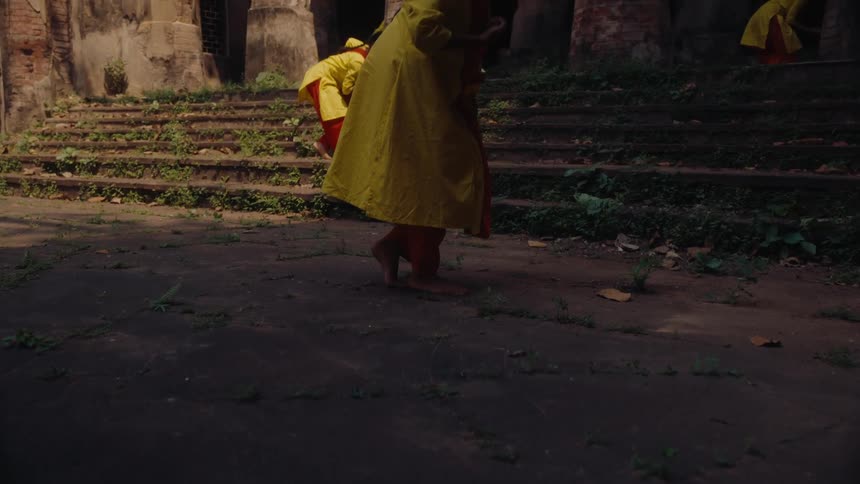 Teen girls in traditional indian attire perform a cultural dance on the steps of an old weathered building with tall columns