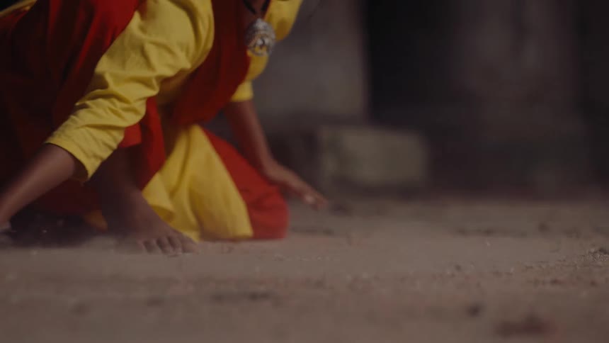 A woman drags her finger across the floor inside a building at midday stirring up dust that swirls around the air