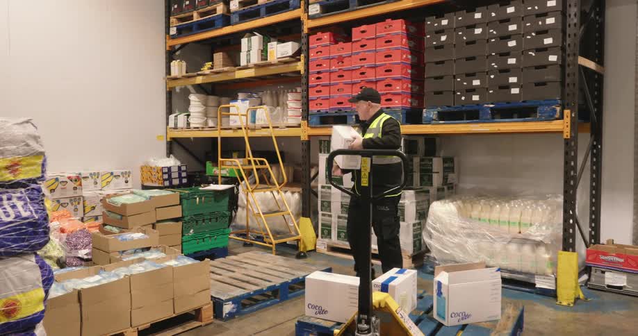 A warehouse worker climbs up a ladder after picking up a product to refill stock and update inventory