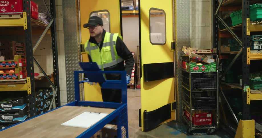 A man pushes a cart full of boxes in the warehouse