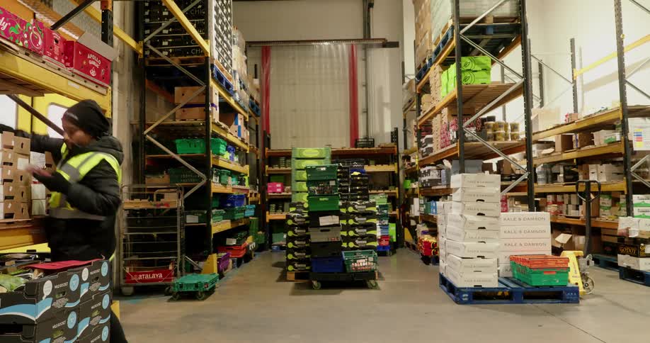 A timelapse captures warehouse workers rapidly organizing and moving boxes in a large wellstocked storage area