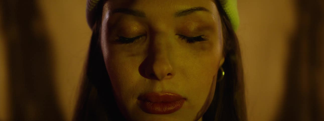 Closeup of a woman with closed eyes under fastmoving warm lights creating a surreal vibe