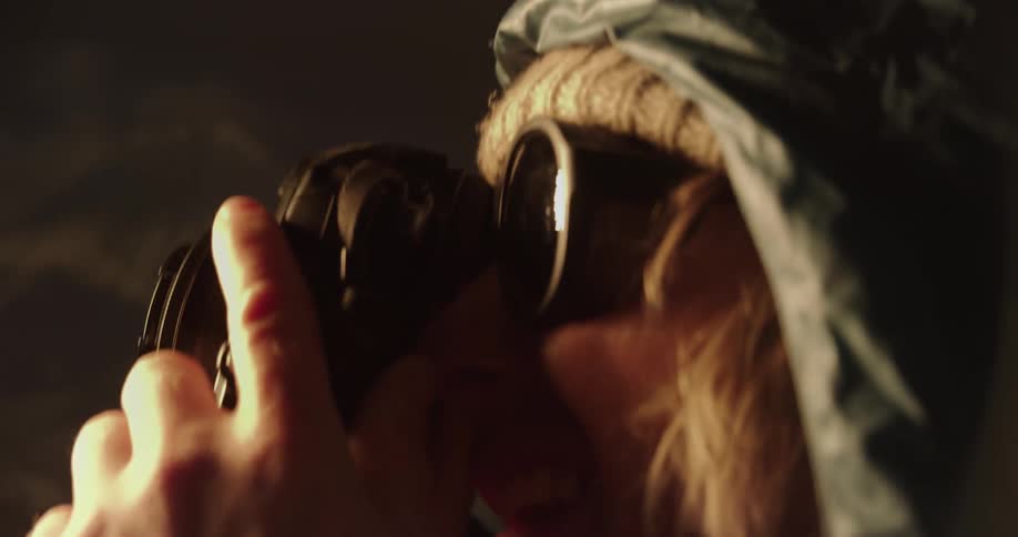 A man wearing a hat and sunglasses is taking a photograph at night