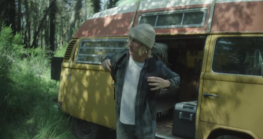 A man puts on his backpack and hikes in the woods