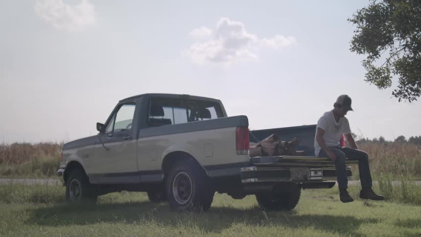 Man sitting in the back of a pickup truck standing up