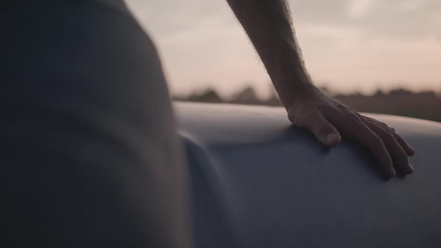 Close up hand of person sitting hood truck parked countryside sunset