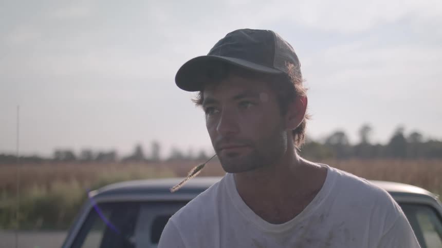 A man is leaning against his car outside