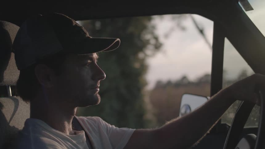 A man is driving his pickup truck past a field