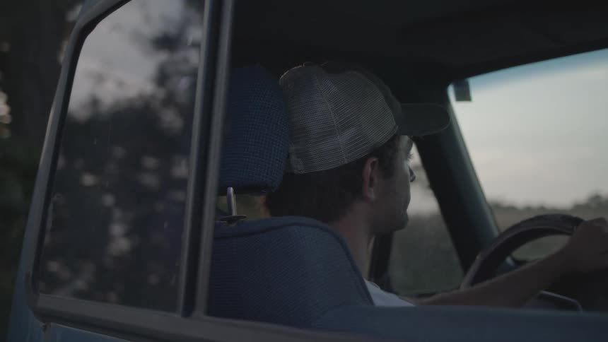 A man is driving a pickup truck on a cloudy day