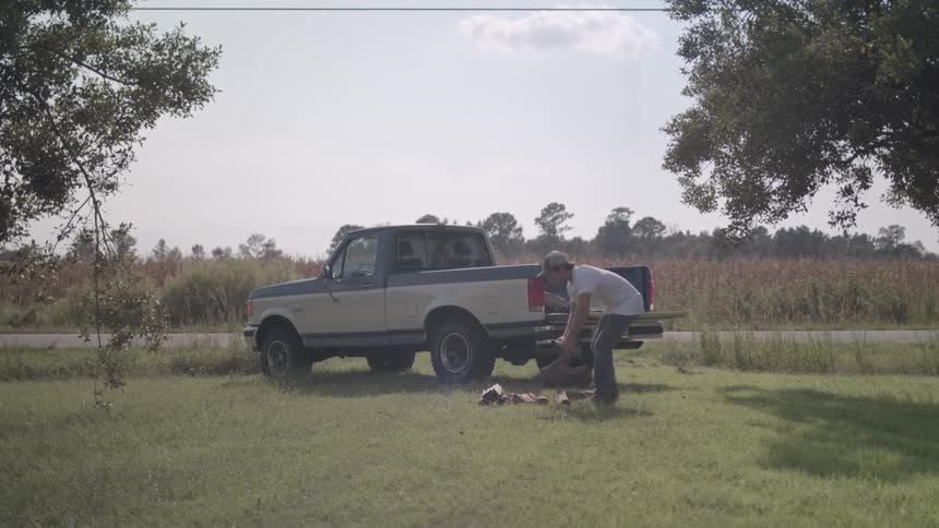 Man putting logs of firewood into a pickup truck