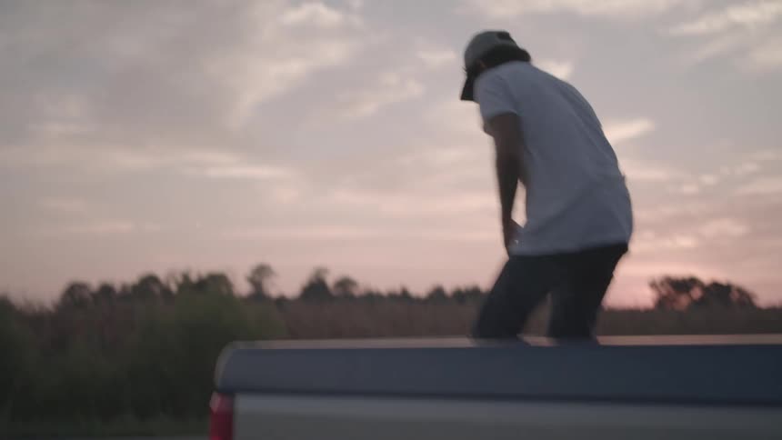 Man in cap standing on back of pickup truck removing firewood