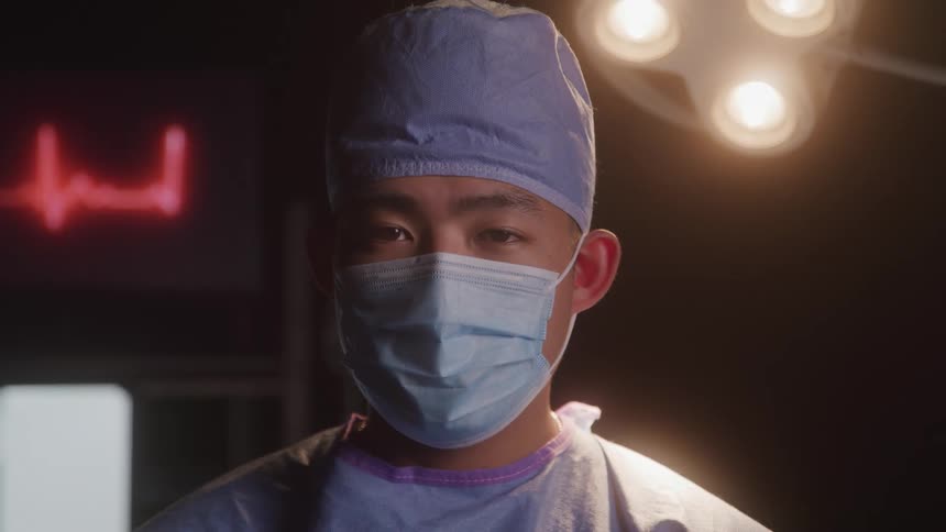Doctor standing still in an operating room staring intently ahead