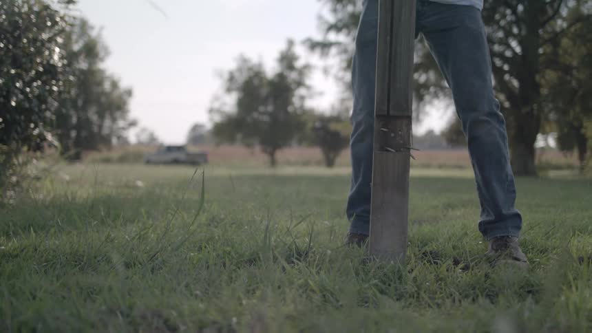A man picks up a wooden post