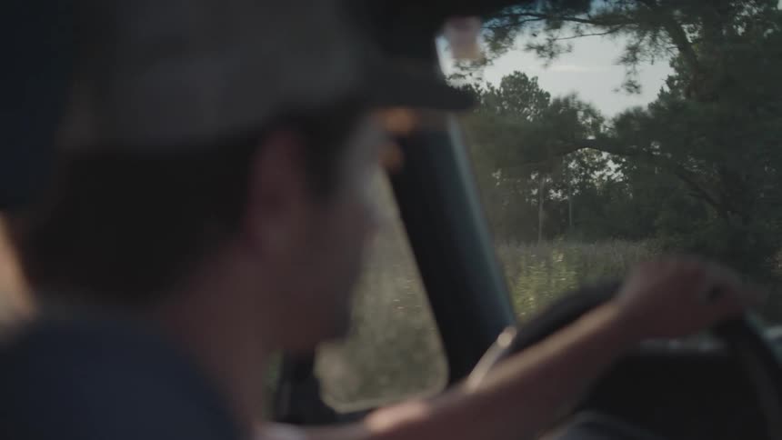 Man in cap driving a vehicle in a natural area