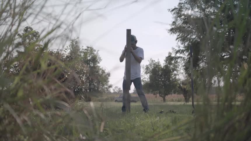 A man plants a post in the field