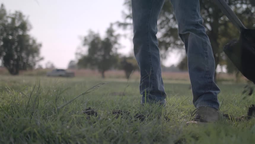 Person with a shovel digging a hole in the grass